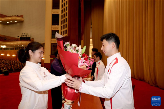 11月15日，一名學生代表在報告會上向乒乓球運動員馬龍（右）獻花。新華社記者 李明 攝