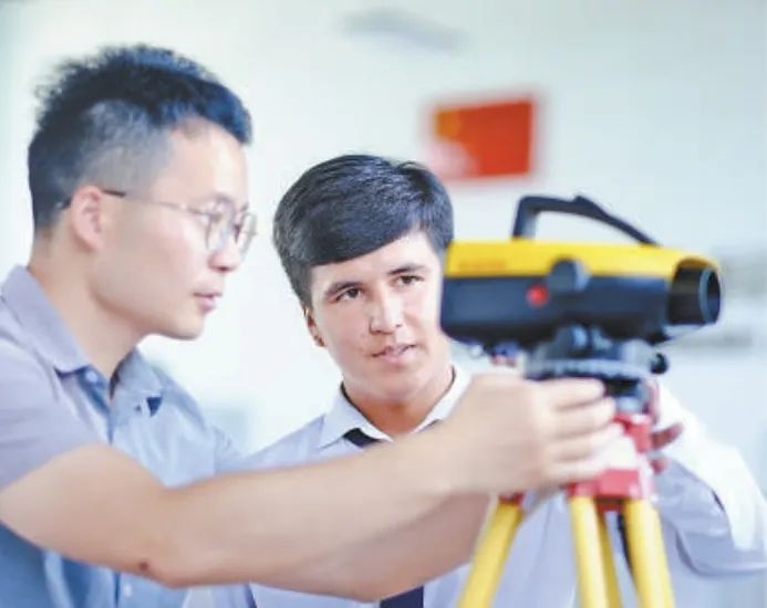 在塔吉克斯坦首都杜尚別的魯班工坊，來自天津城市建設管理職業(yè)技術(shù)學院的老師（左）為當?shù)貙W生提供指導。新華社記者 鄭開君 攝
