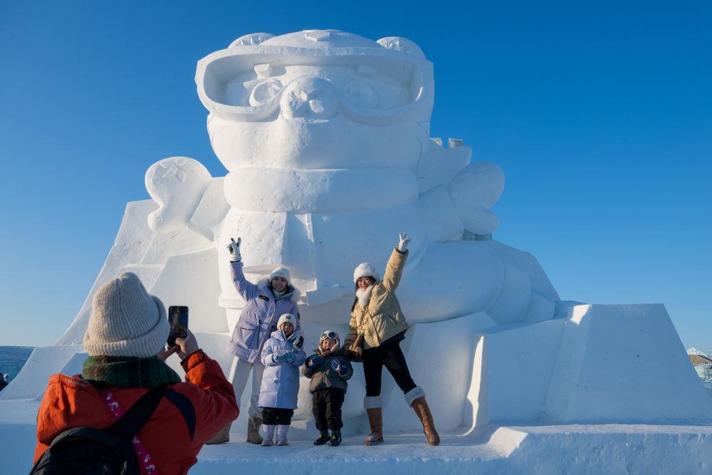 2025年1月3日，在黑龍江哈爾濱冰雪大世界園區(qū)，游客與亞冬會(huì)吉祥物雪雕“濱濱”合影