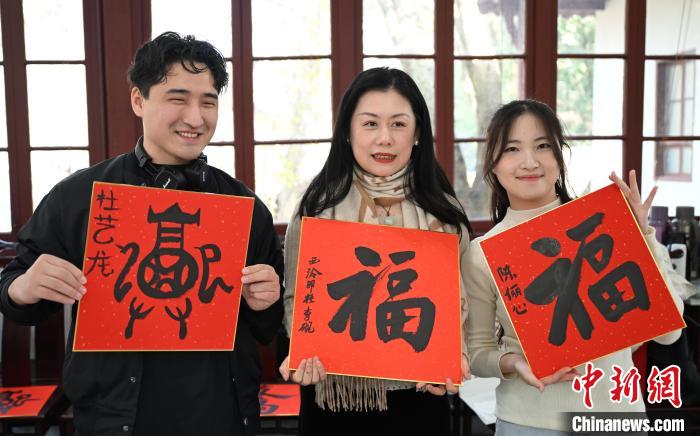1月20日，外籍留學生和西泠印社社員李硯(中)展示各自創(chuàng)作的福貼。當日，來自巴西、馬來西亞、加納、哈薩克斯坦的外籍留學生在浙江杭州西泠印社體驗福貼、春聯(lián)和篆刻，感受古老的中國傳統(tǒng)文化。中新社記者 王剛 攝