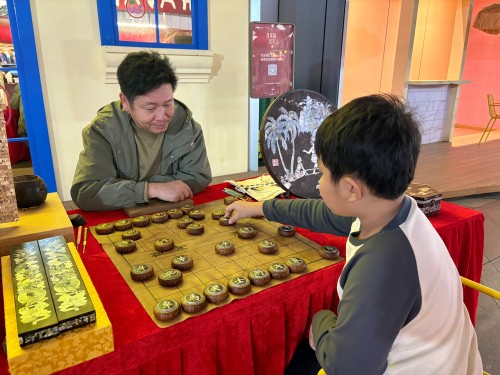 柯秋楓與市民下椰雕象棋。人民網(wǎng) 陳葉欣攝