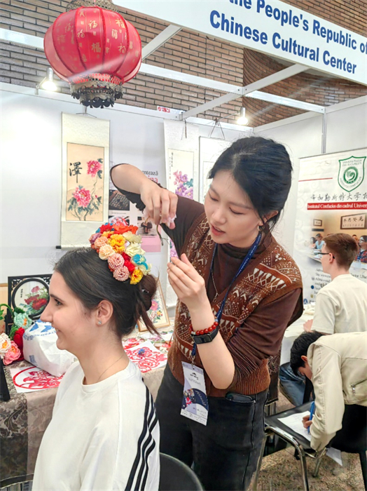 展覽正值羅馬尼亞迎春花節(jié)，國際中文教師志愿者潘婧穎向游客們介紹了國家非物質(zhì)文化遺產(chǎn)——福建泉州的簪花文化。布加勒斯特大學(xué)孔子學(xué)院供圖。