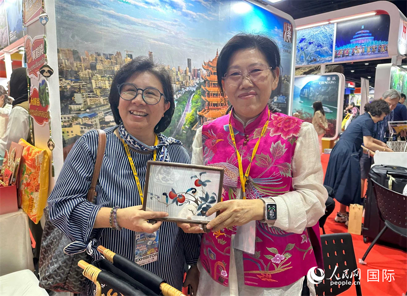 中國“大冶刺繡”傳承人劉小紅（右）參加泰國國際旅游展，向觀眾介紹中國非遺刺繡針法。人民網(wǎng)記者 簡承淵攝