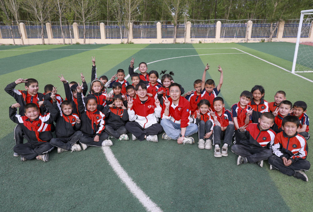 4月23日，在新疆克州阿圖什市哈拉峻鄉(xiāng)謝依特小學(xué)，支教教師王俊文（中左）、李軻凡（中右）和學(xué)生在一起。